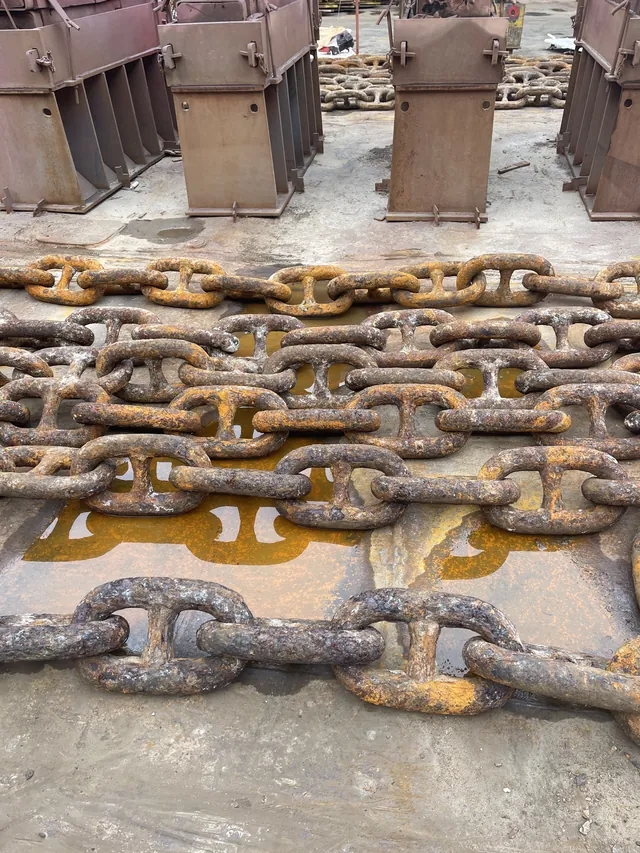 Anchor chain links ranged on the dock floor for inspection. Shanghai, February 2025.