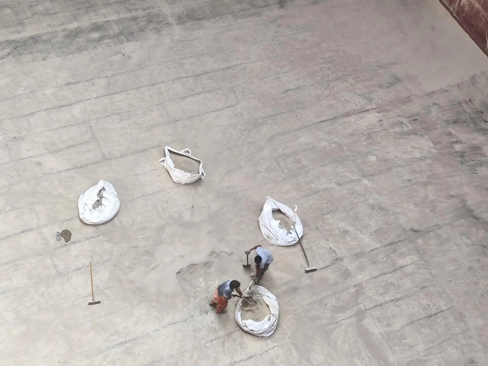 Crew sweeping cargo residue into bags on the tank top, seen from above